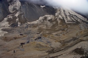 Photo by Pavel Izbekov. John Eichelberger leads a group of students to the rim of the Katmai caldera in the 2011 International Volcanological Field School. To get there, students must traverse the top of a glacier, insulated by a thick layer of pumice from the massive 1912 eruption of the volcano.