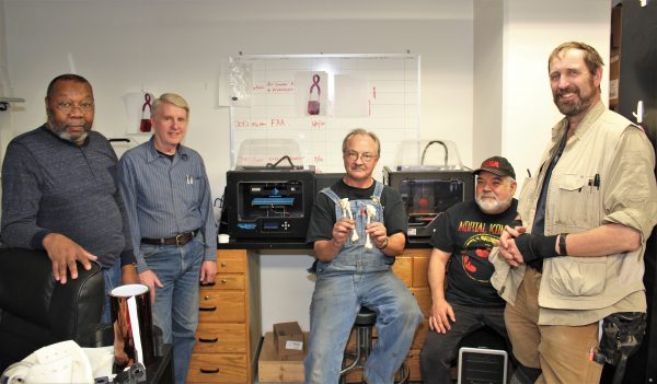 Photo by Josh Hartman. In the machine shop, (Left to right) Greg Shipman, Phil Woodard, Kurt Laiti, Jesse Atencio and Dale Pomraning stand in front of the 3D printers that they used to build the femur model for the Fairbanks Memorial Hospital Surgeon. Laiti holds the two models — one of the fractured femur and one of the healthy femur. The models were scaled down to half the size of the real femur for printing.