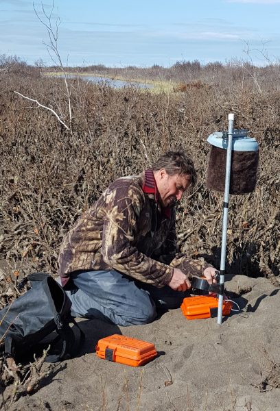 Taylor Stinchcomb photo.  UAF Assistant Professor of Wildlife Biology Todd Brinkman installs a recording device to monitor the noise of aircraft activity on the North Slope.
