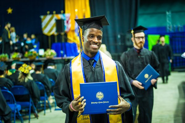 Farimang Touray Jr. is all smiles as he poses for his family's cameras during the 2017 UAF Commencement at the Carlson Center Saturday, May 6, 2017. UAF photo by JR Ancheta.