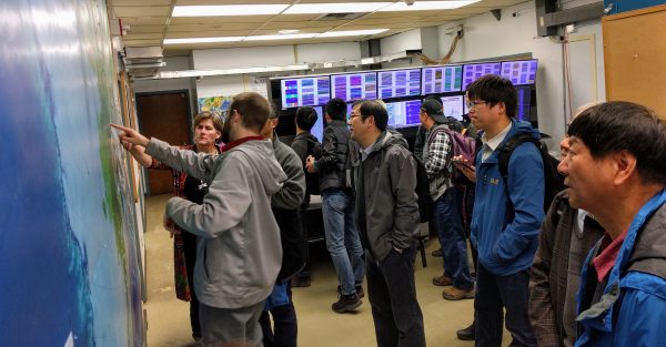 Photo courtesy of EarthScope.  Seismologist Matt Gardine shows the SinoProbe group and accompanying tour members the distribution of seismic stations and the real-time data display at the Alaska Earthquake Center on May 22.