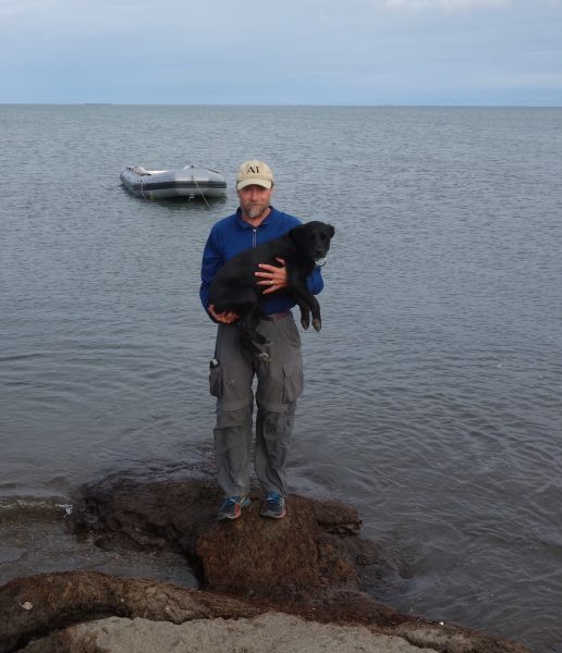 Photo by Becky Baird.. Ned Rozell and his dog Cora with the Arctic Ocean and Prudhoe Bay in the background on the day they finished their trans-Alaska hike.