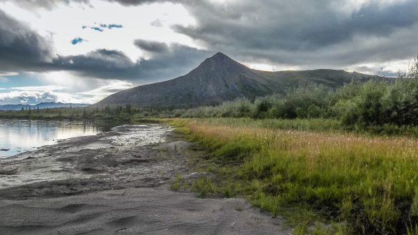 Photo by Mike Fallon. A mountain rises above the Sheenjek River in July.