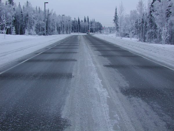 Photo by Doug Goering.  Frost-free stripes on Thompson Drive are created by thermosyphons beneath the road designed to keep the underlying permafrost frozen.
