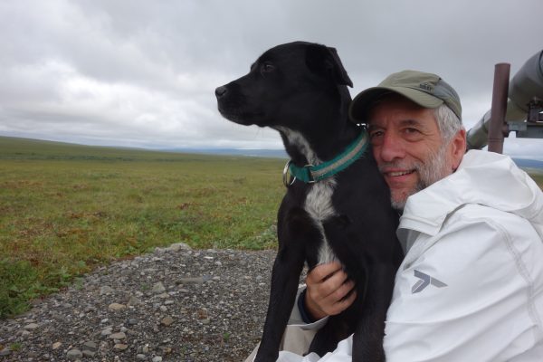 Photo by Ned Rozell.  Eric Troyer, who walked for a week with Ned Rozell on the path of the trans-Alaska oil pipeline, hugs Cora the dog, who has done the entire trip this summer.