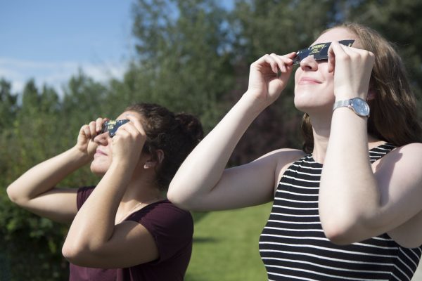 Photo by Meghan Murphy. Undergraduate students Betsy Lokken, left, and Sabrina Bishop view the sun with special glasses that protect their eyes from the harmful rays.