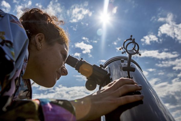 Photo by Meghan Murphy. Undergraduate student Betsy Lokken looks safely at the sun through a Newtonian Reflector telescope, which has a sun filter on the front. The filter blocks out out 99.999 percent of incoming light to make it safe.