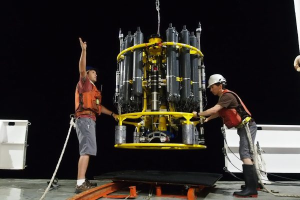 Photo courtesy of Andrew McDonnell.  Jim Burkitt, left, and Andrew McDonnell recover an instrument during night operations on a ship in the equatorial Pacific Ocean.