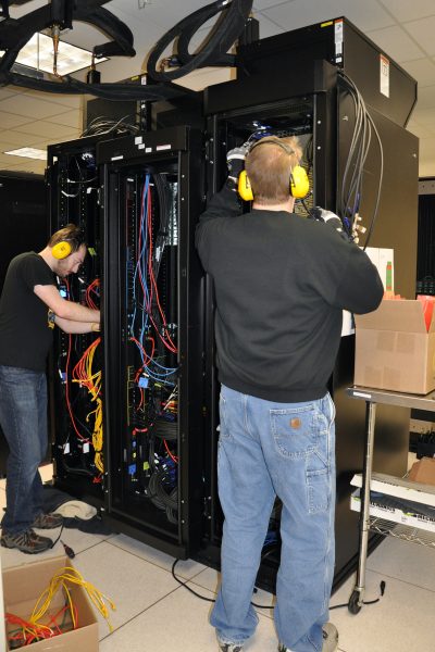 Photo courtesy of UAF GI Research Computing Systems.  Tim Slauson, left, and Liam Forbes install components to increase the capacity of the Chinook computer system in February 2017. Chinook is operated by Research Computing Systems at the University of Alaska Fairbanks Geophysical Institute.