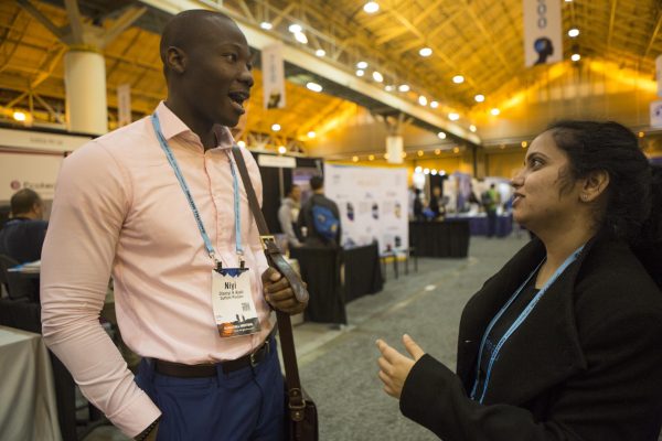 Photo by Meghan Murphy. Mitali Chandnani runs into Niyi Ajadi in an exhibitor aisle at the AGU Fall Meeting in New Orleans. Ajadi recently graduated from UAF and now has a job. Chandnani is on the search for one.