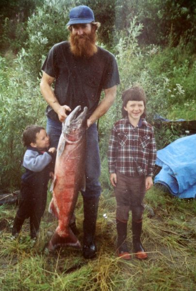 Photo courtesy of Randy Brown.  Randy Brown holds a chinook salmon at his family's fish camp on the Yukon River in 1989 or 1990 with his sons Gabe, at right, and Jed.