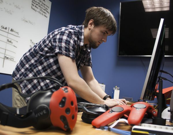 Photo by Tom Moran/Alaska NSF EPSCoR. Recent University of Alaska Fairbanks graduate Tristan Craddick sets up a virtual reality experiment. A VR headset and controllers sit in the foreground.