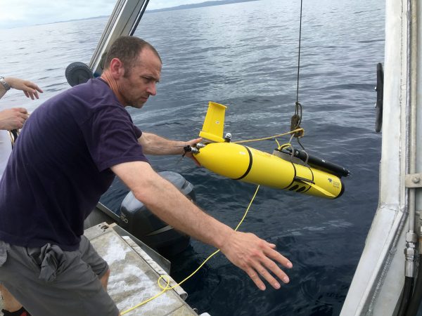 Photo courtesy of Louis St. Laurent. Harper Simmons deploys a wave glider into the ocean off the coast of Palau.