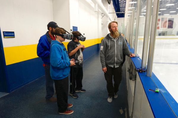  Photo by Patty Eagan. Students wearing first-person view goggles fly unmanned aircraft through a hula hoop obstacle course at UAF's Patty Center ice arena. Nick Adkins, with UAF's Alaska Center for Unmanned Aircraft System Integration, watches.