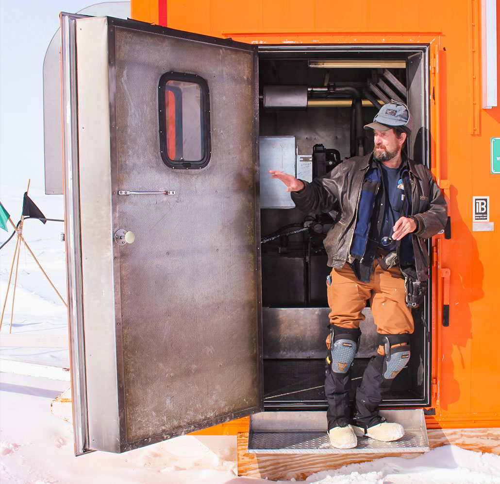 Dale Pomraning stands in the doorway of BOB — the Big Orange Box — at Windless Bight. BOB is a former walk-in freezer with foot-thick walls. It houses computers and provides solar and diesel-fired generator power to nearby infrasound sensors that help detect nuclear detonations. Pomraning wears kneepads because sometimes he must crawl to reach places inside BOB’s tight quarters. Photo courtesy of Dale Pomraning.