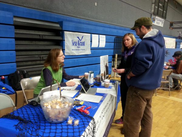 Photo courtesy of Alaska Sea Grant. Alaska Sea Grant Marine Advisory agent Torie Baker speaks with fishermen in Cordova, Alaska, in 2015 about participating in a study about fishermen's health led by a University of Washington researcher, Dr. Debra Cherry.