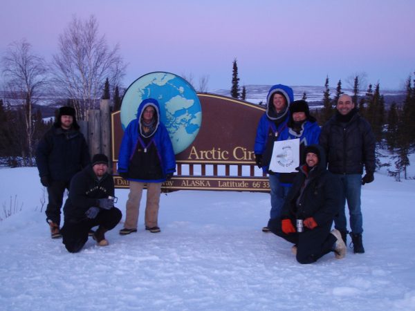 Photo courtesy of Darrin Marshall. From left, Ryan West, Shawn Freitas, John Whittington, Doug Morrow, Bernie Tao, Darrin Marshall and Andy Soria pose at the Arctic Circle pullout on the Dalton Highway, where they camped in March 2009 to test the cold-weather performance of Permaflo Biodiesel.