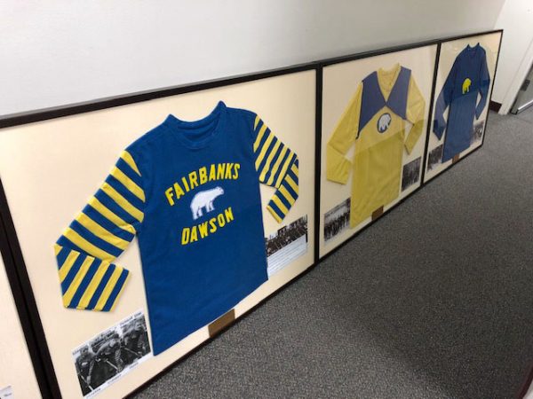 Photo by Kristin Baysinger. Framed reproductions of historic hockey sweaters line the wall at the Carlson Center, where six reproduced and two original sweaters will be displayed.