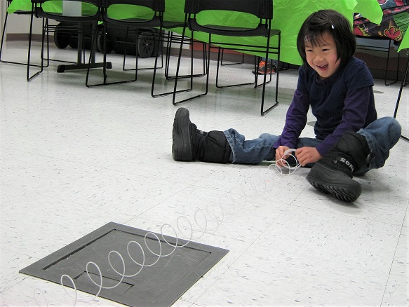 UAF photo. A visitor uses a Slinky to model seismic waves during an earthquake program at the museum.
