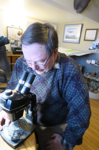 Photo by Cheryl Bradley. Geologist Tom Bundtzen uses a binocular microscope to look at one of Alaska's oldest rocks, which formed more than 2 billion years ago and was found near Iditarod.