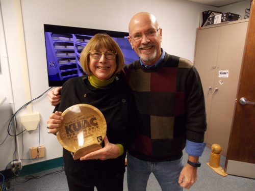 Photo by Nancy Tarnai. Patty Kastelic receives KUAC's top volunteer award for 2019 from Keith Martin, KUAC general manager, in the public broadcasting station's offices.
