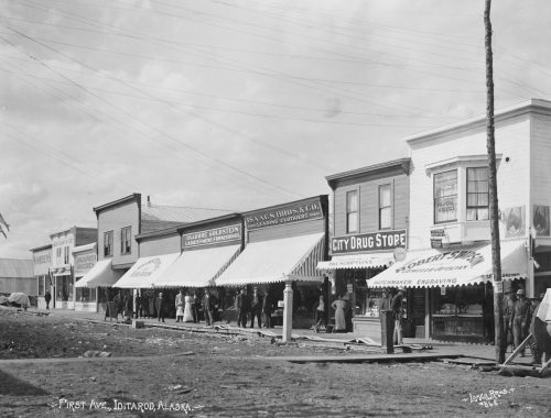 Photo by Lomen Brothers, UAF Archives. First Avenue in the town of Iditarod, pictured here around its peak in 1911, featured storefront awnings and wooden sidewalks.