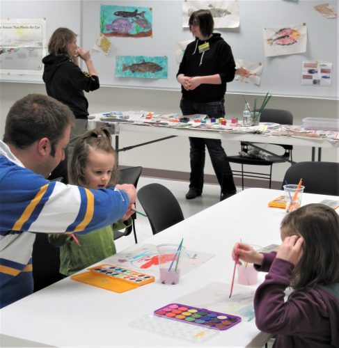 UAF photo. Children and adults make fish art and explore how salmon migrate during a program at the museum.