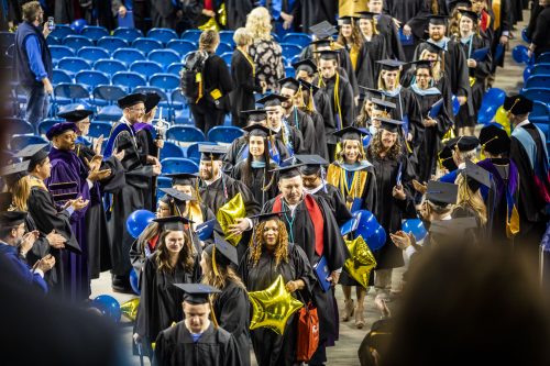 Flanking the graduates in two lines, members of the faculty congratulate the graduates during the 2019 commencement recessional at the Carlson Center. UAF photo by JR Ancheta.