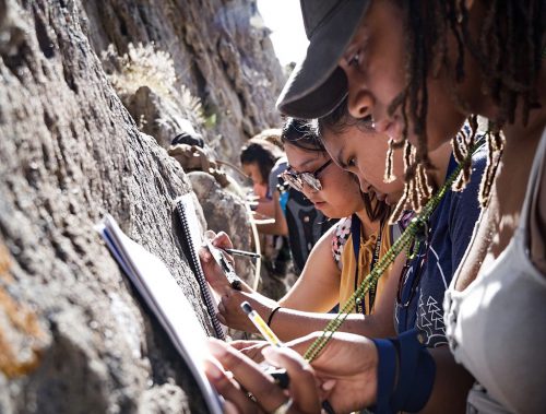 Photo by Leif Van Cise. GeoFORCE Alaska students describe sedimentary rocks at Dinosaur National Monument in Utah and measure the orientation of the layers in order to construct a geologic map.