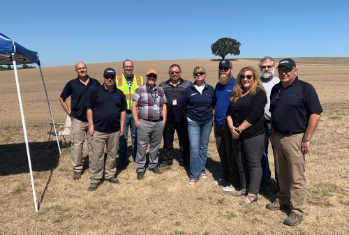 UAF photo by James Parrish. A group gathers to witness the inaugural flight at Northwest UAV's test site in Oregon in September 2019. The group includes, from left, Joe Gibbs and David Jackson with Northwest UAV, Tim Klein with Klein Engineering, Rich Davis and Terry Wilmeth with the Federal Aviation Administration, Heather Sorenson with Northwest UAV, Nick Adkins with UAF ACUASI, Heather Peck with the Oregon Department of Aviation, Tom Elmer with UAF ACUASI, and Chris Harris with Northwest UAV.