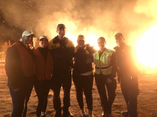 Police officers and staff members standing in front of a large bonfire.