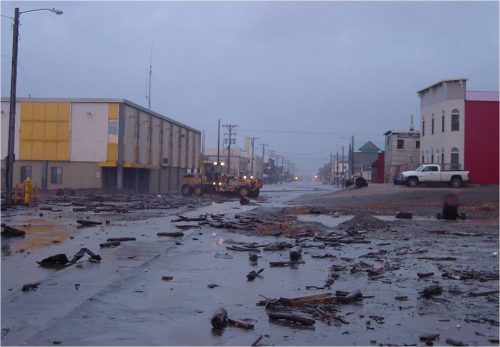 Photo by Dave Atkinson. Debris lies on a street in Nome, Alaska, after it was inundated by storm flooding. New research suggests that high wind events in Nome could triple by 2099.