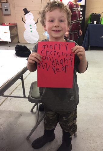 Photo by Jessica Bird. A young participant at the 2018 Holidays at the Farm event shows off the holiday letter he wrote to an overseas soldier.