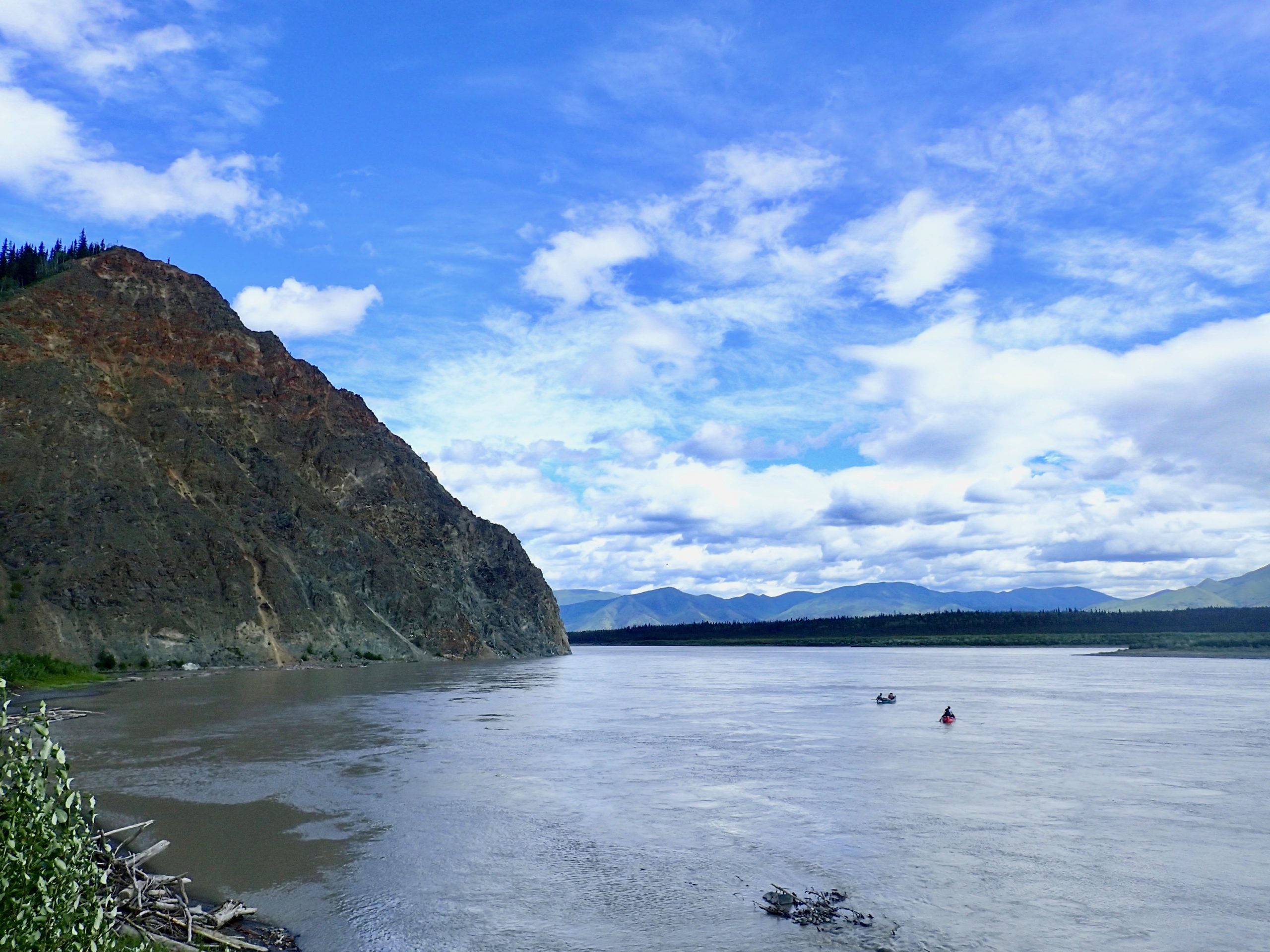 Photo by Ned Rozell. Canoeists take to the Yukon River as it flows past the bluff just downstream from Eagle, Alaska, in summer 2019.