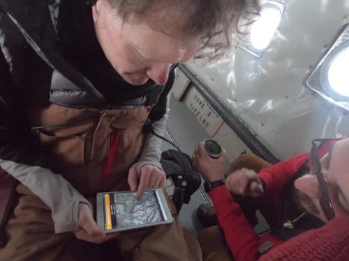 Photo courtesy of Arctic Submarine Lab. Hajo Eicken, director of the UAF International Arctic Research Center, points to ice floes on a tablet while he and Michael Thomas, of Ukpeagvik Inupiat Corp., conduct a survey flight to help pick the ICEX 2020 camp location.