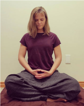 Wendy Martelle with her hands in her lap, palms facing up and her eyes close while she meditates.
