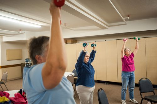 Photo by Edwin Remsberg. Members of a StrongWomen strength-training class practice with weights.