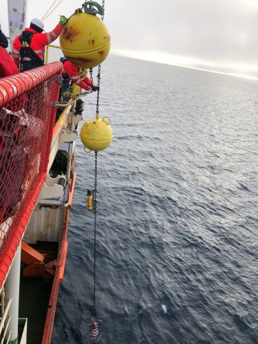  Photo courtesy of the Nansen and Amundsen Basins Observational System. Large yellow floats connected to several scientific sensors are lowered over the edge of a ship in the Arctic Ocean.