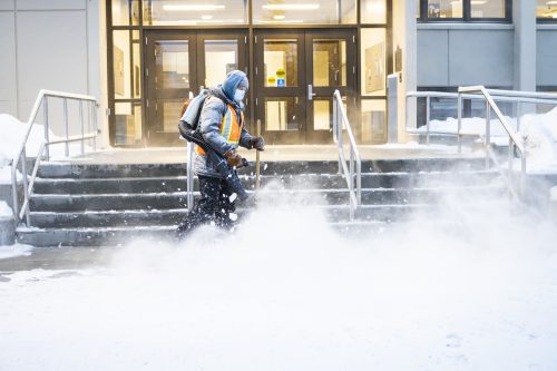 A worker blows snow off the steps leading to Constitution Hall in February 2021. UAF photo by JR Ancheta.