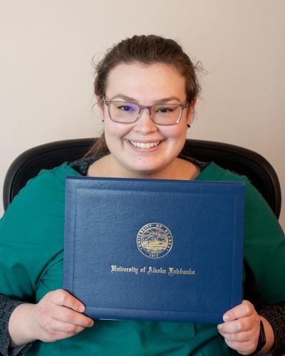 Photo courtesy of Fairbanks Native Association. A student who is part of the Fairbanks Native Association's NACTEP program holds a UAF diploma cover.