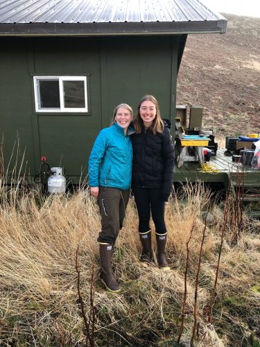 Photo by Heather Renner, Alaska Maritime National Wildlife Refuge. Biologists Briana Bode, left, and Katie Stoner pose after being dropped off at their cabin on Chowiet Island in May 2021. The women recently experienced a magnitude 8.2 earthquake there, not far from the epicenter.