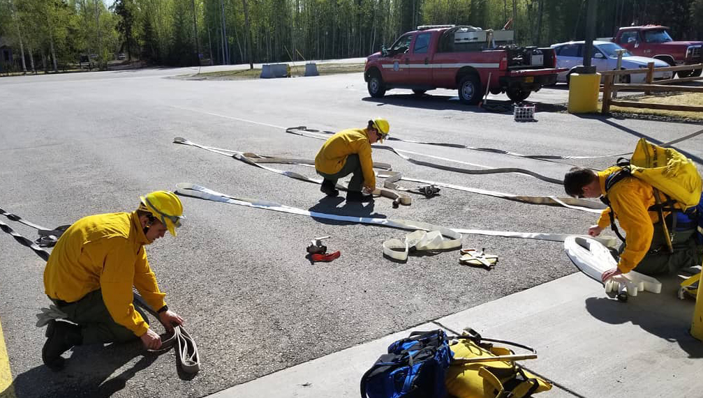 three firefighters folding hoses