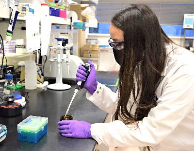A woman in a lab coat works in a laboratory