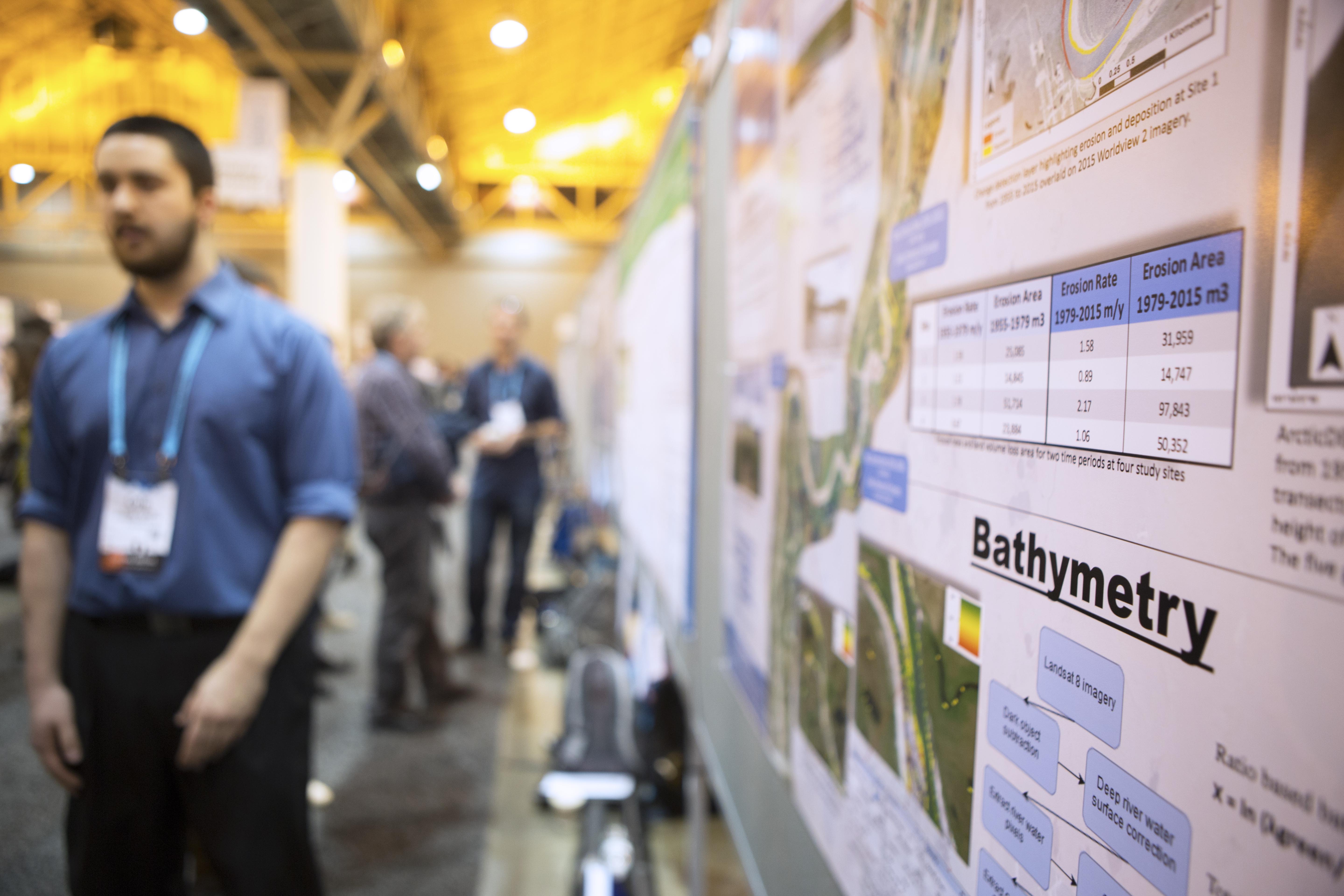 A researcher stands by his poster at a science conference.
