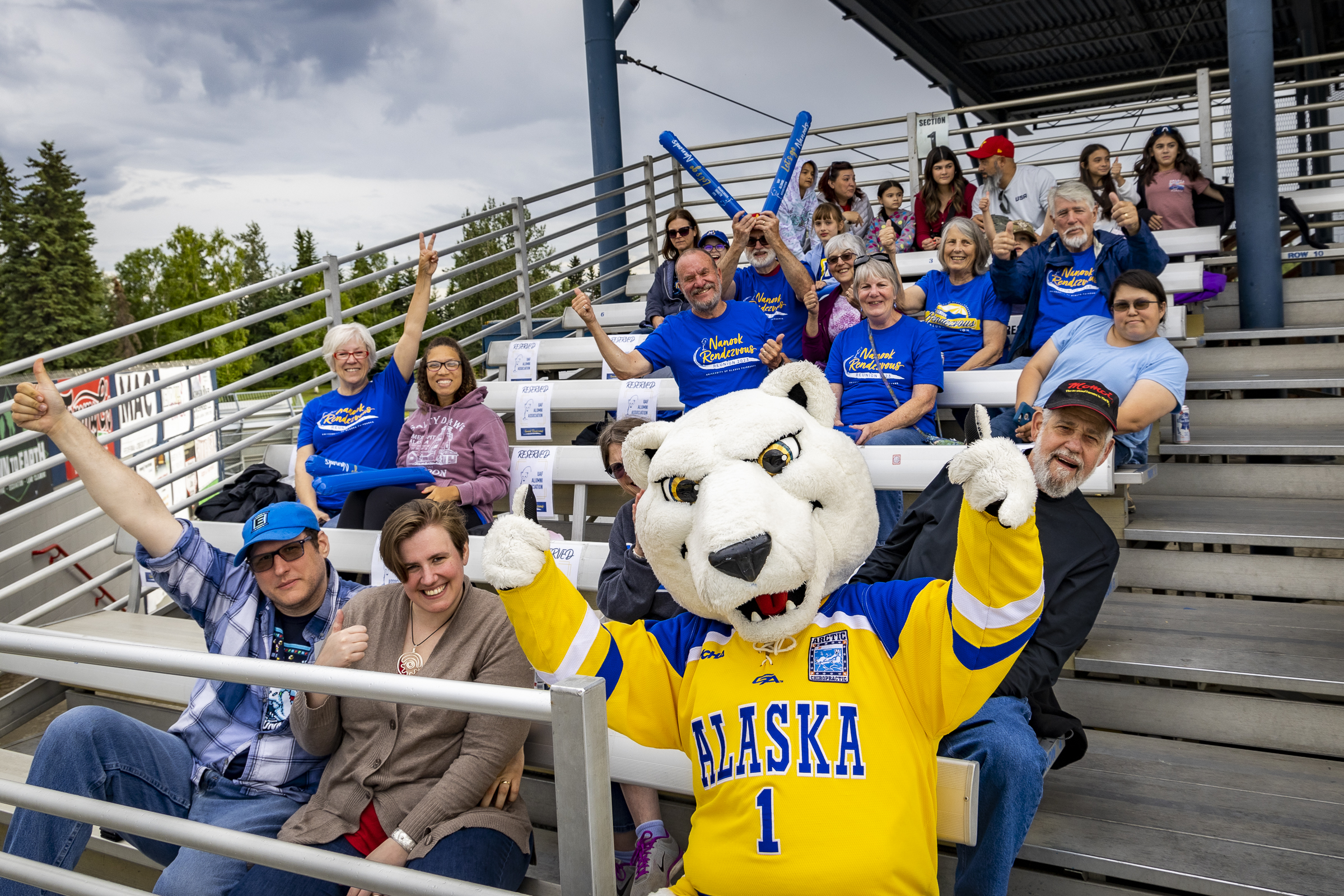 People cheer in the stands at a game with a polar bear mascot in costume.