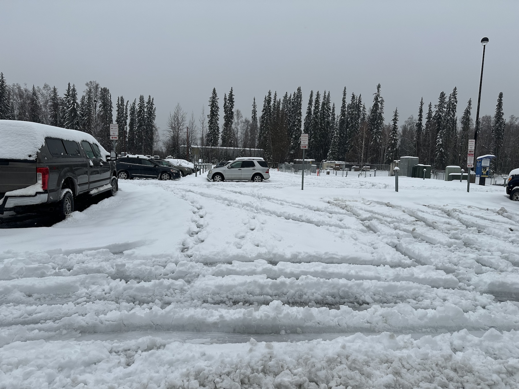 Cars sit in a parking lot covered with slushy snow.