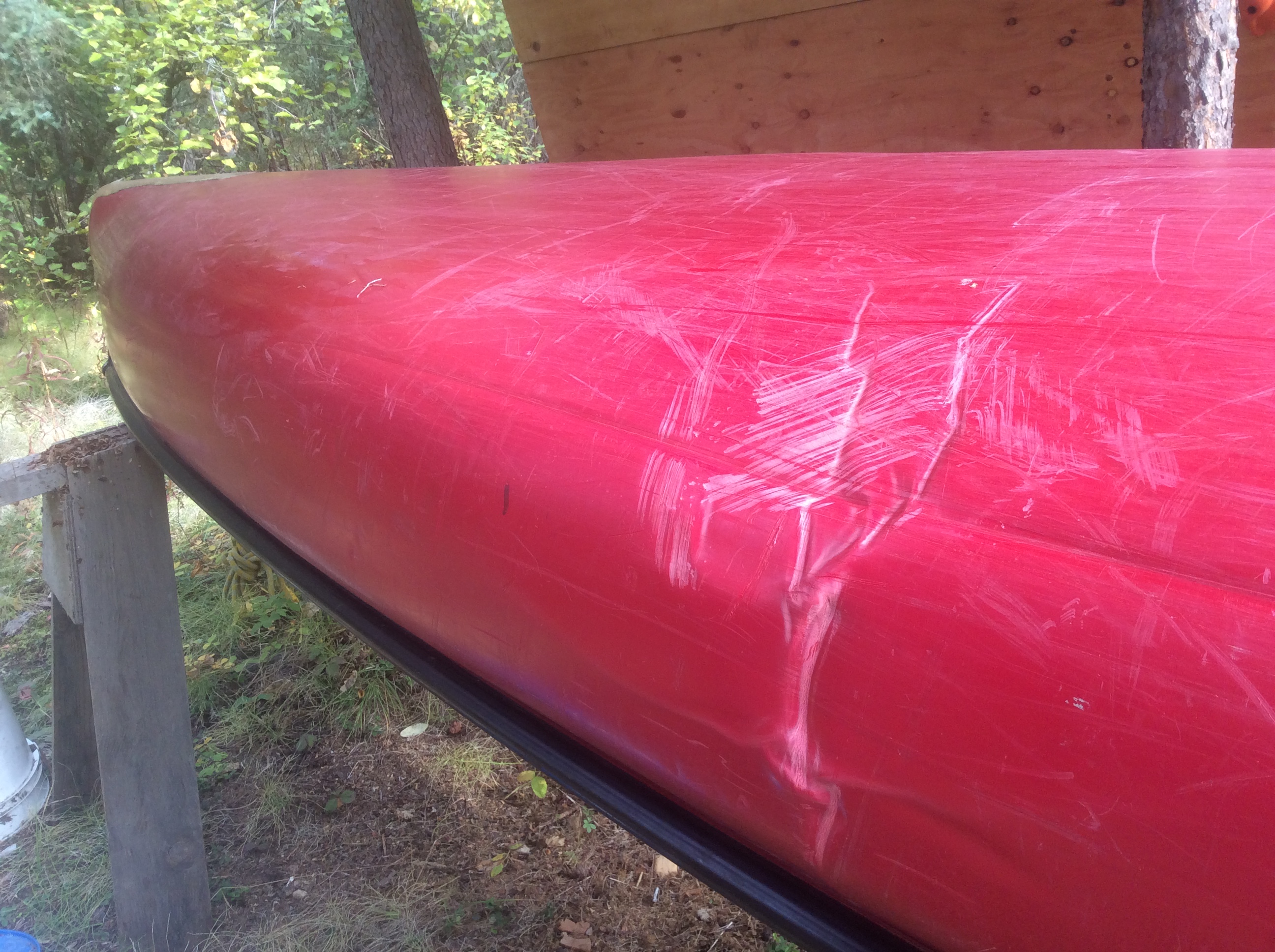 Wrinkles mar the surface of a red plastic canoe's bottom.