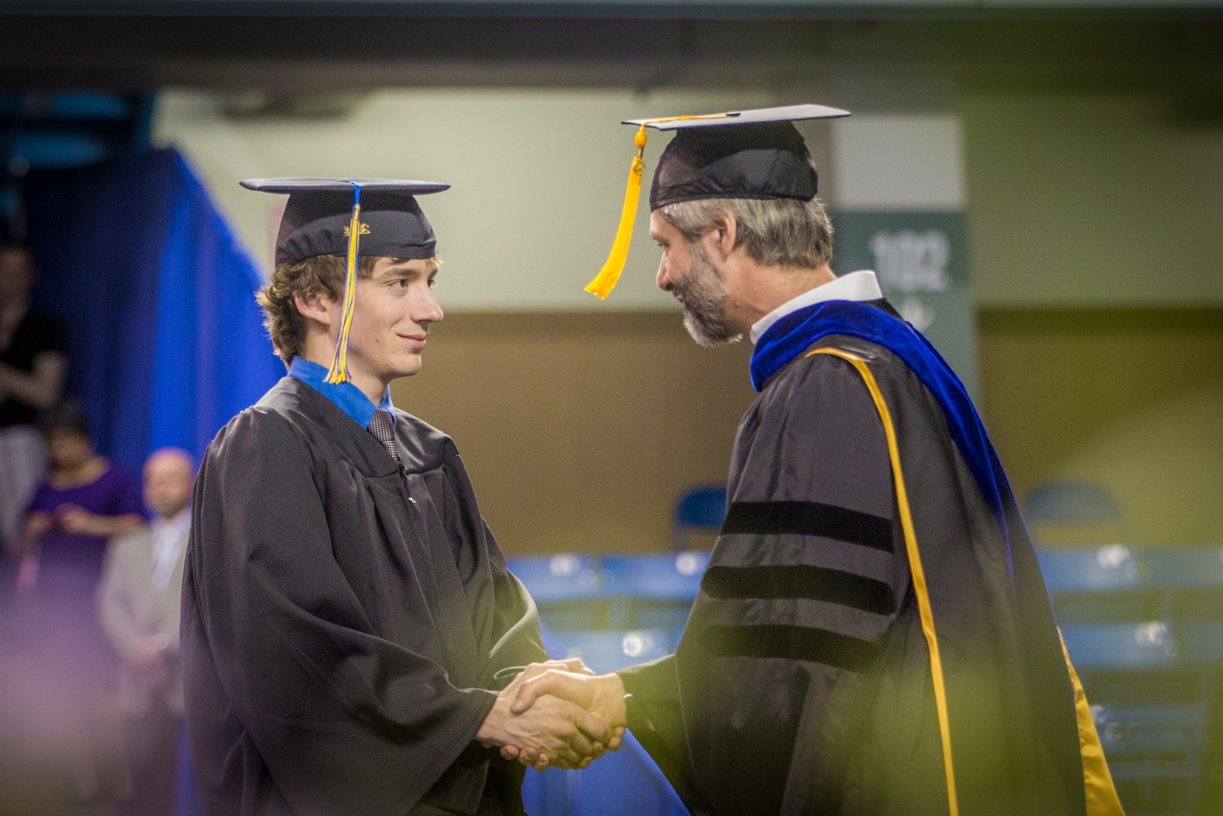A UAF students shakes hands with a professor during the commencement ceremony.