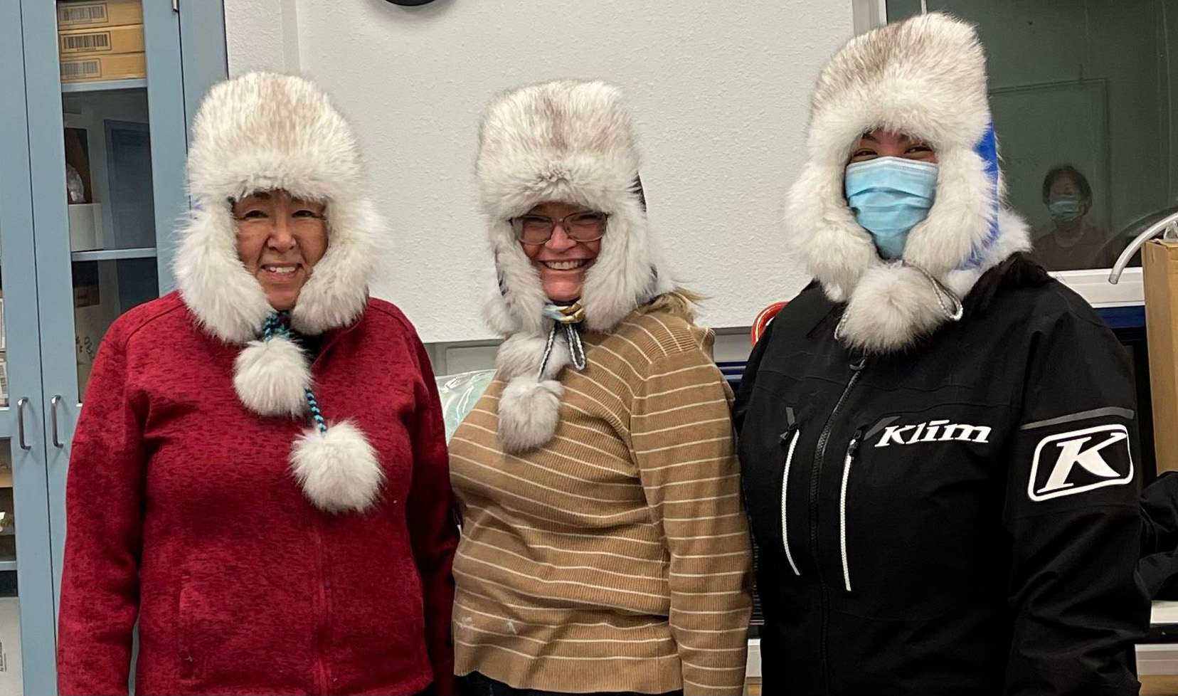 Three women wear fur hats