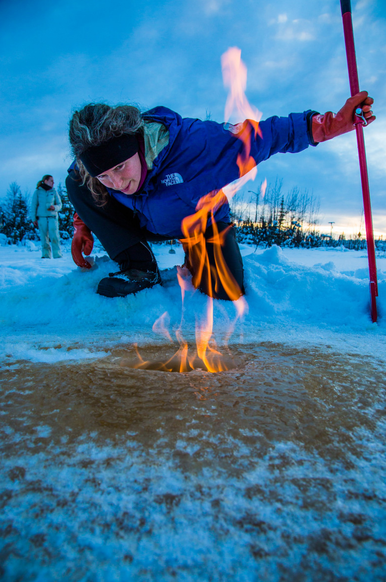 Katey Walter Anthony inspects flaming methane gas seeping from a hole in the ice on the surface of a pond on the UAF campus in February 2016.